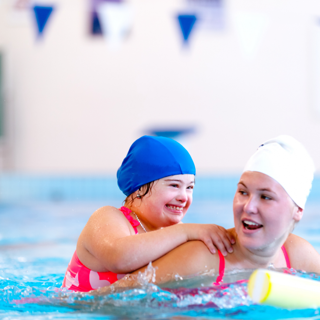 A swim teacher giving a young student a piggyback in the pool