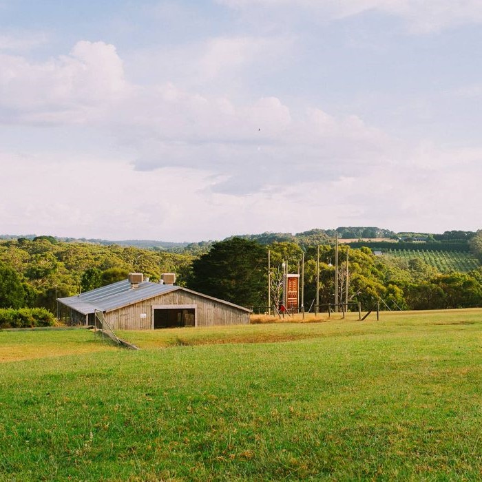 Valley with large barn and climbing wall in the distance.