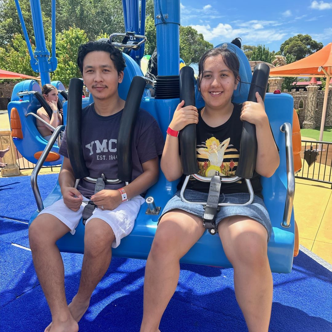 Y support worker and participant smiling on a rollercoaster