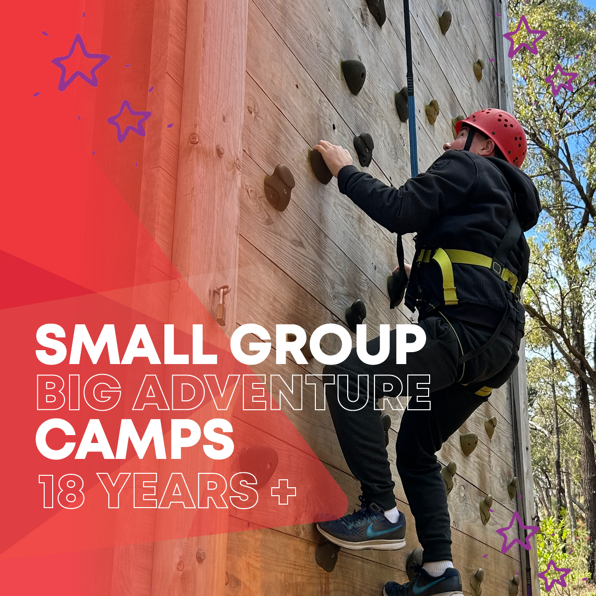 Camper is climbing a boulder wall in harness and helmet