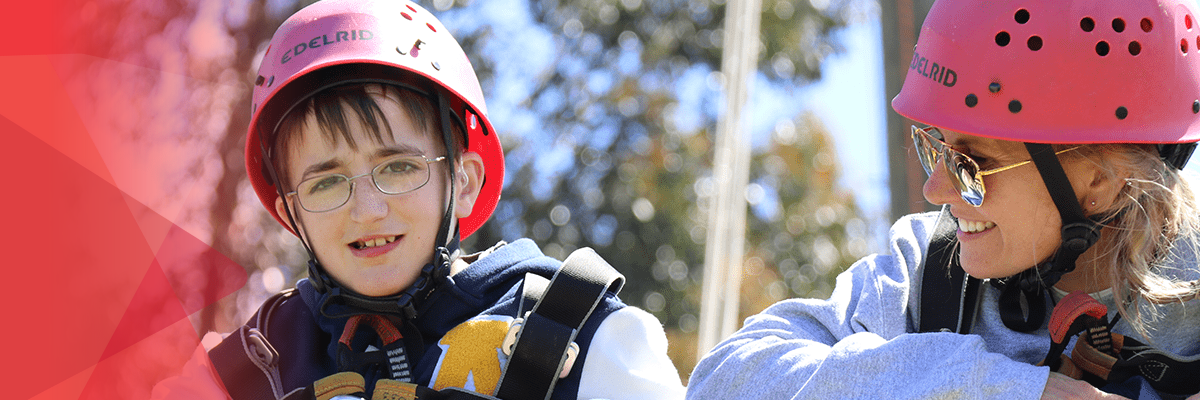 Happy child and camp support worker wearing helmets