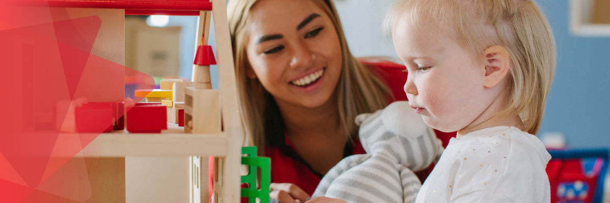 A early years worker smiles as she watches her pre-school aged child play